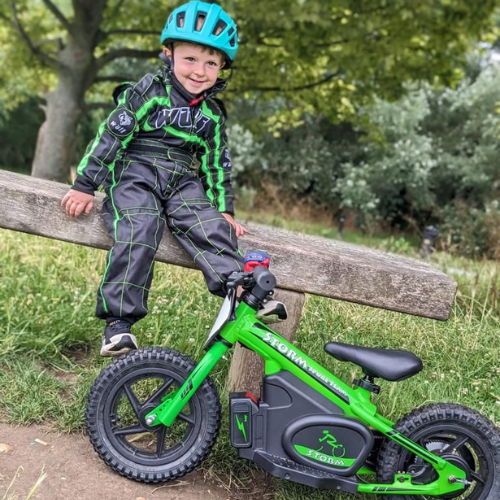  Small boy wearing a green wulfsport suit, sitting next too a green storm electric balance bike.