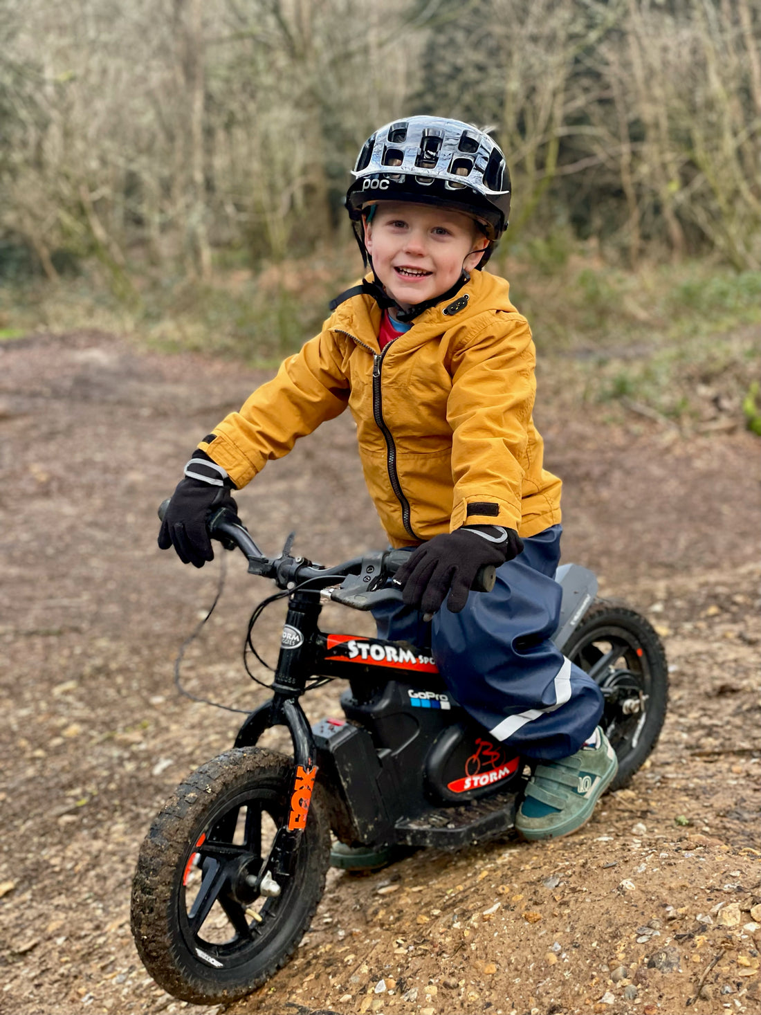  Small boy wearing a black helmet riding a black 12" storm electric balance bike